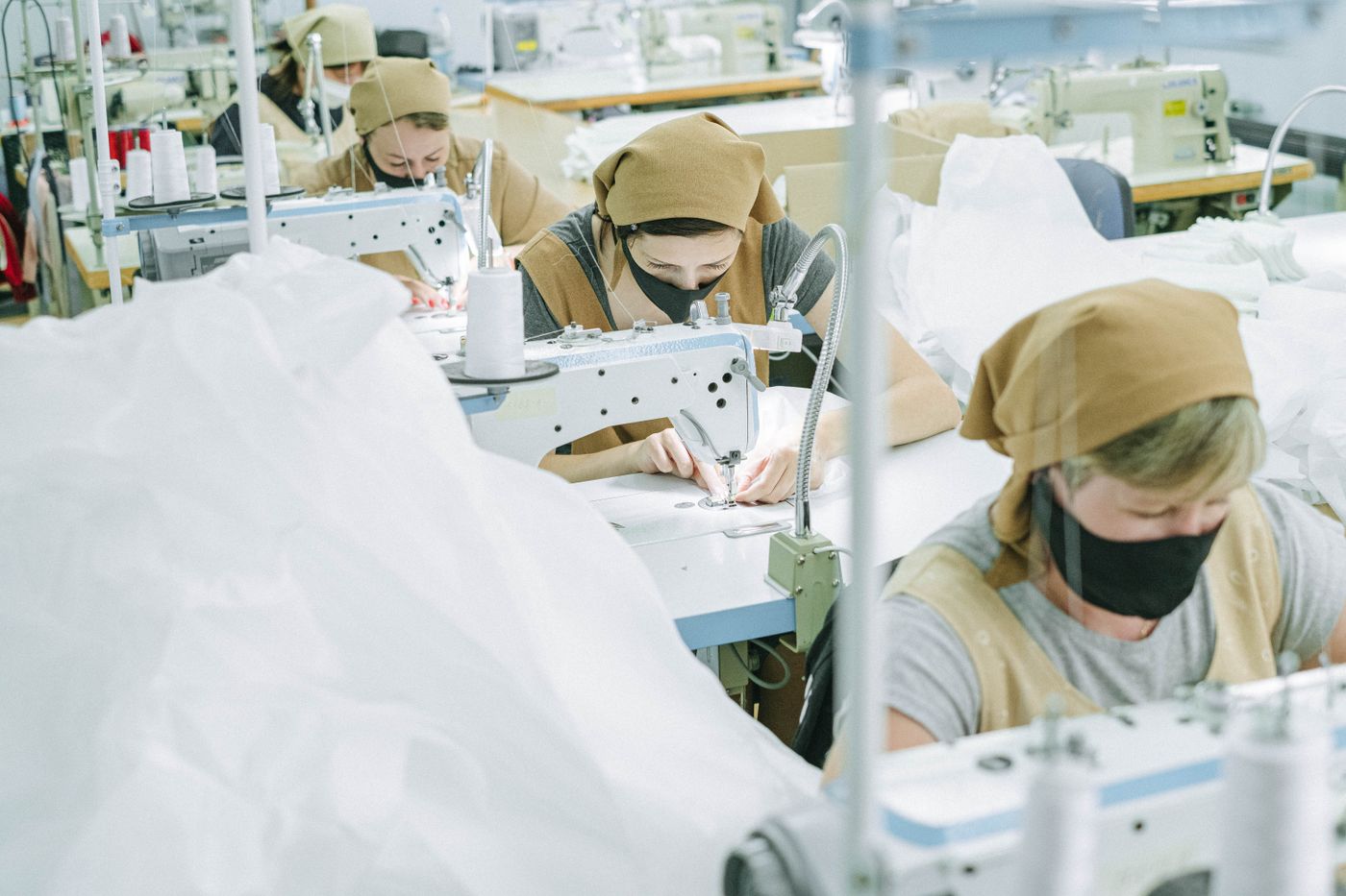 Garment workers sewing fabric at industrial machines; stock photograph by Ivan S